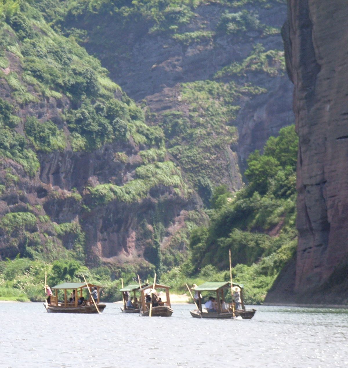 A bamboo raft drifting down the Luxi River at Longhushan, past the red Danxia cliffs
