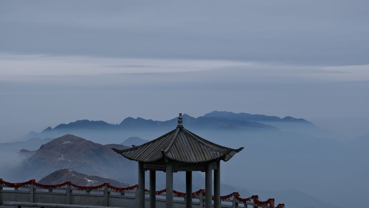 A ridge-top pavilion on Wugongshan rising above a sea of clouds at dawn, the classic reward for staying overnight