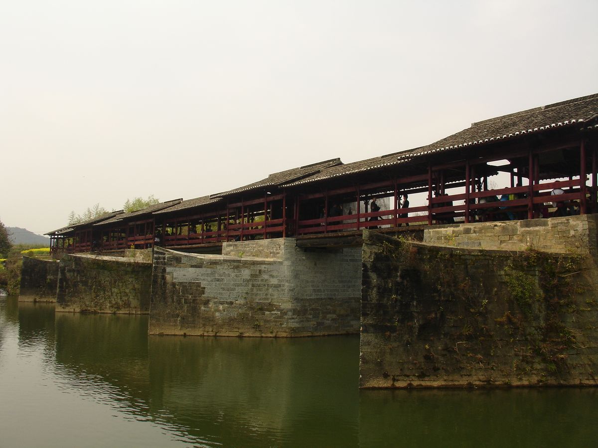The Qinghua Rainbow Bridge (彩虹桥), a Song-dynasty covered wooden bridge on boat-shaped stone piers over the river at Qinghua, Wuyuan